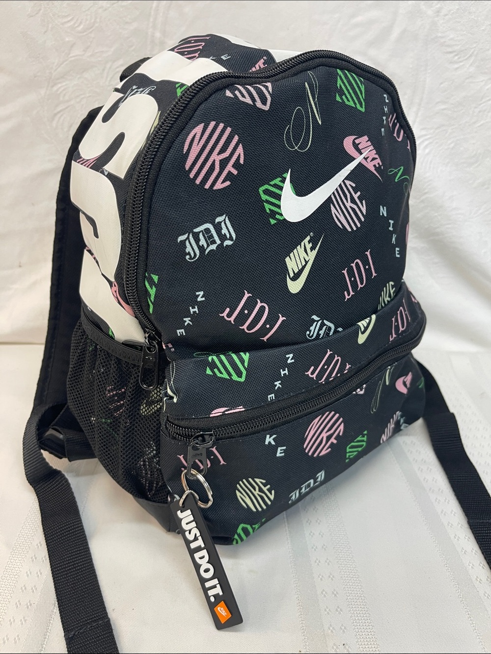 Nike Brasilia JDI Mini Backpack in black with a colorful logo print.